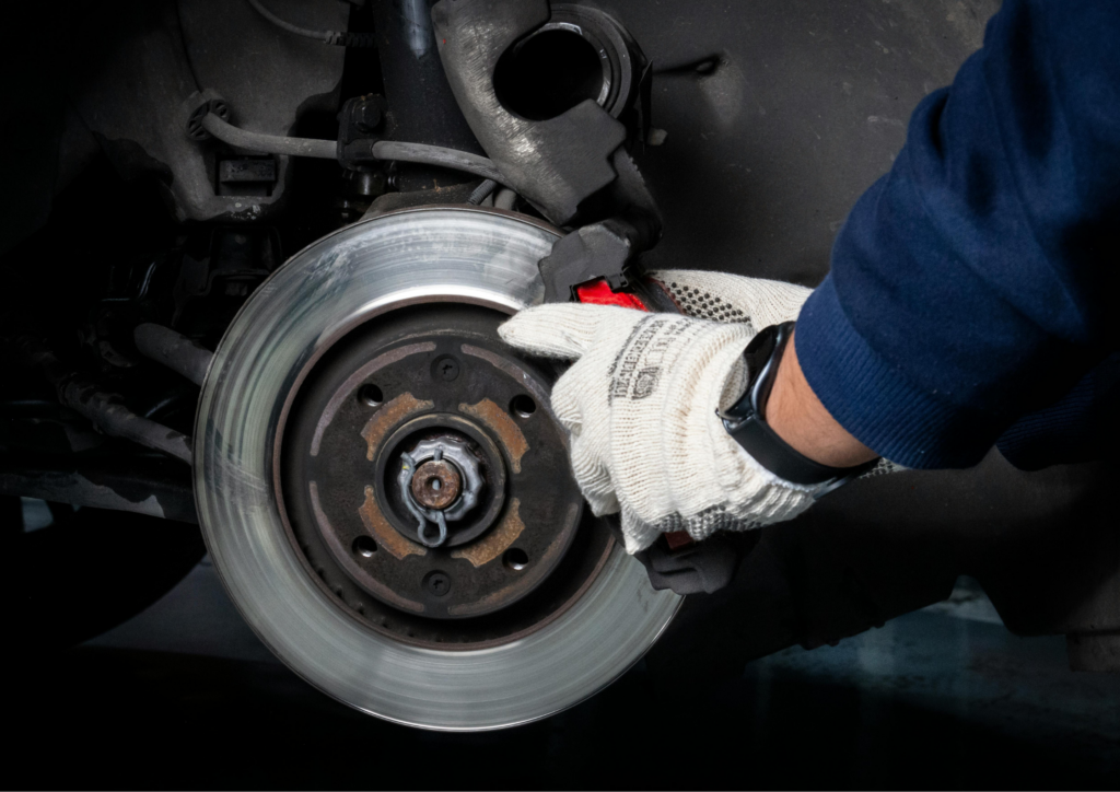 Close-up van een grote gesleufd remschijf met rode remklauw achter een beadlock velg van een lifted 4x4 terreinwagen.