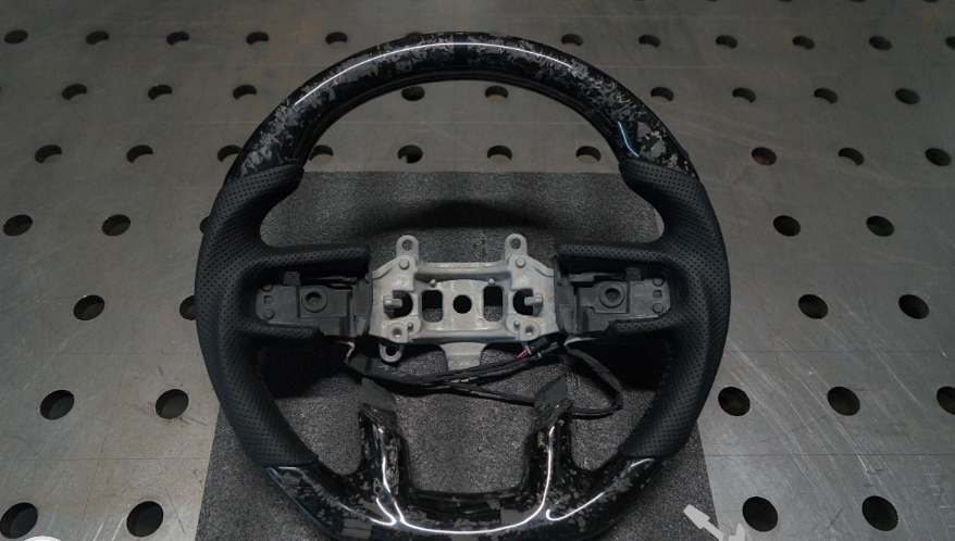 Close-up van een custom suede stuurwiel met stiksel detail en quick release naaf gemonteerd in een offroad 4x4 kooi.